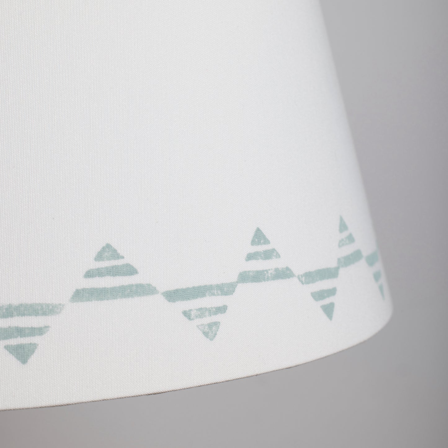Close up of a cream lampshade with a blue triangle pattern – bold geometric empire lampshade in cream cotton, perfect for modern interiors.