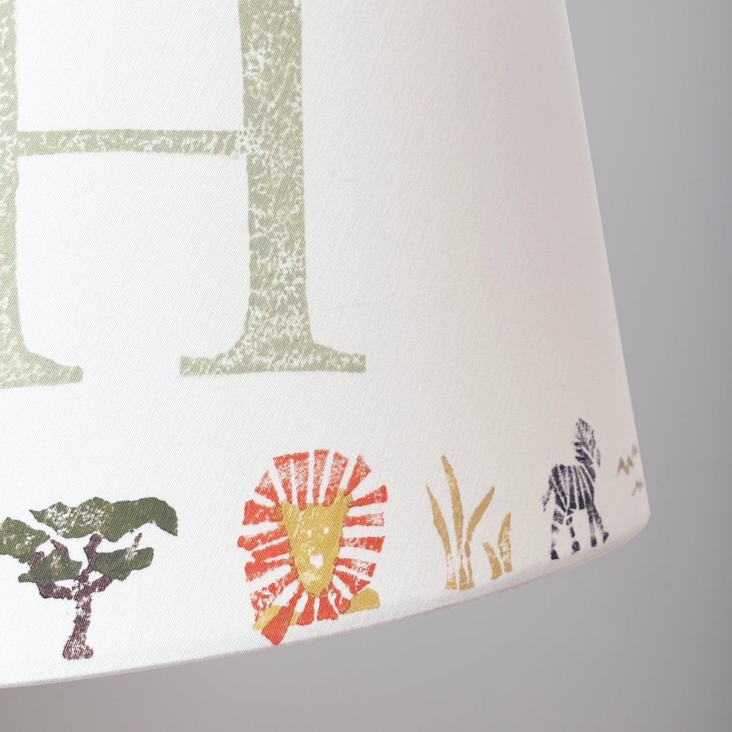 Close-up of colourful safari lampshade with lion, zebra and tree prints. Personalised lampshade detail showing handmade safari animal design, ideal for animal lampshade in kids bedroom decor.
