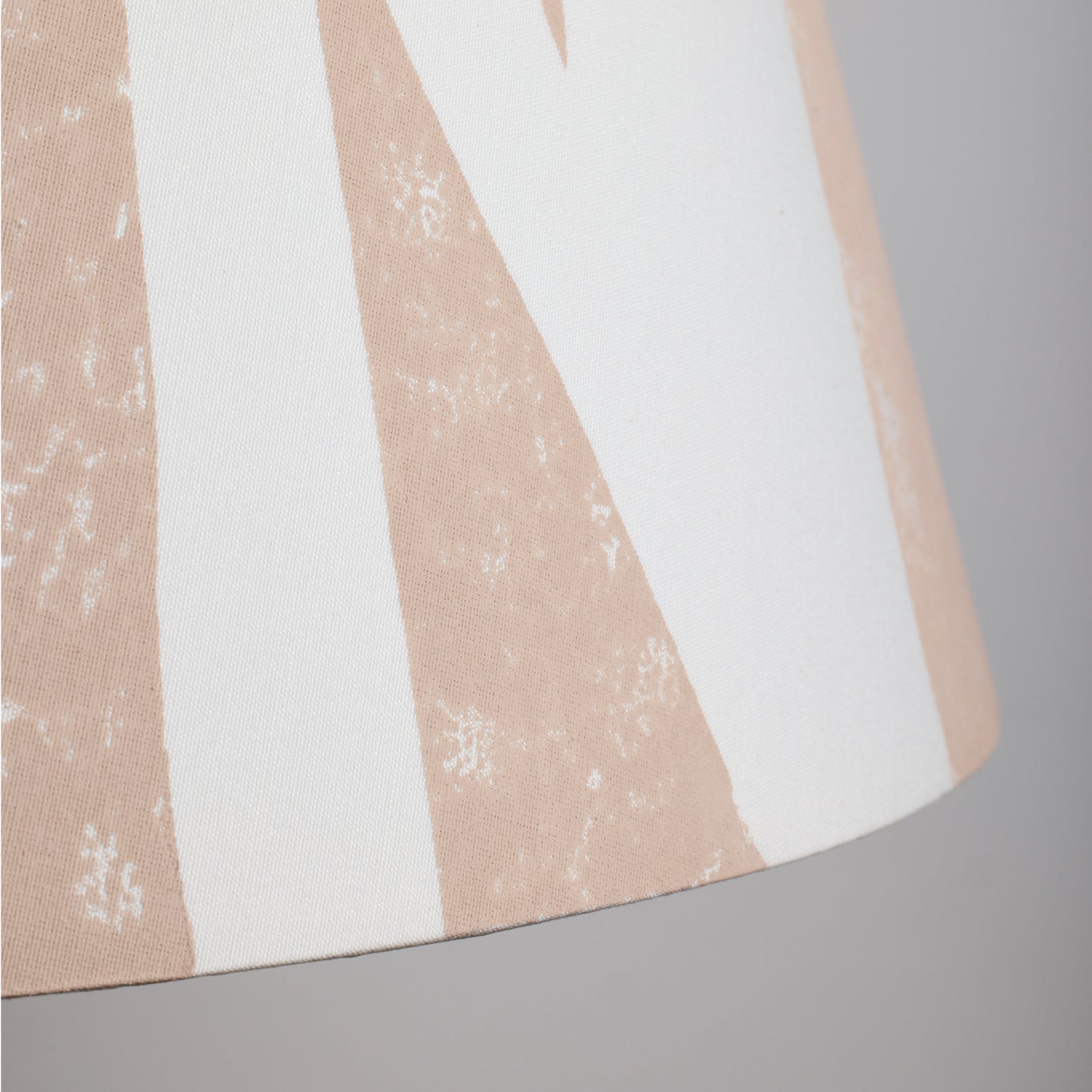 Close-up of cream lampshade with geometric triangle pattern in soft pink. This empire shade combines bold lampshade design with a neutral finish, ideal for modern and classic interiors.
