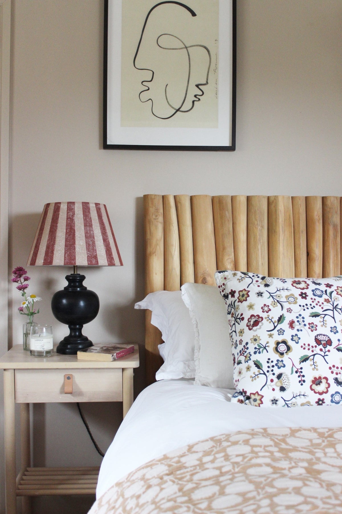 Empire lampshade with bold burgundy and pink stripes, styled on a black table lamp beside a bed with a wooden Tikamoon headboard. A colourful lampshade and classic striped lampshade for bedrooms.