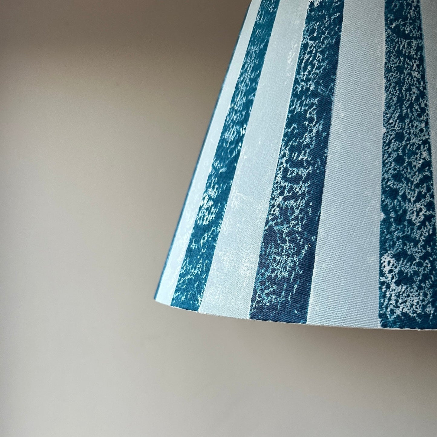 Close-up of blue bold stripe lampshade in empire shape with textured finish. A colourful lampshade design, part of Studio Zef’s striped lampshades UK collection for modern striped lighting.