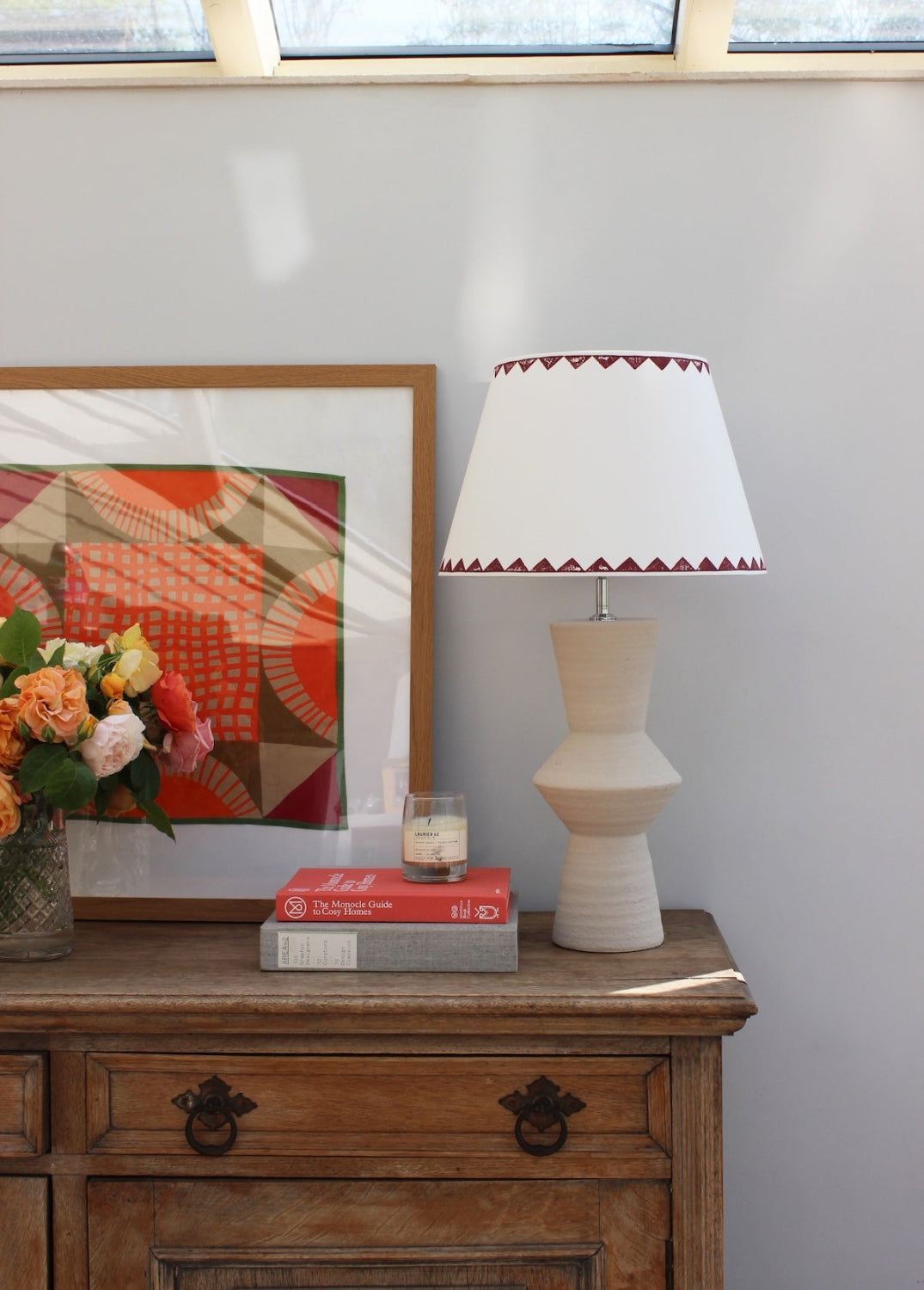 Large empire lampshade in cream with burgundy triangle pattern sitting on a sculptural stone lamp base, a bold lampshade with geometric detail, ideal for colourful lampshade styling.