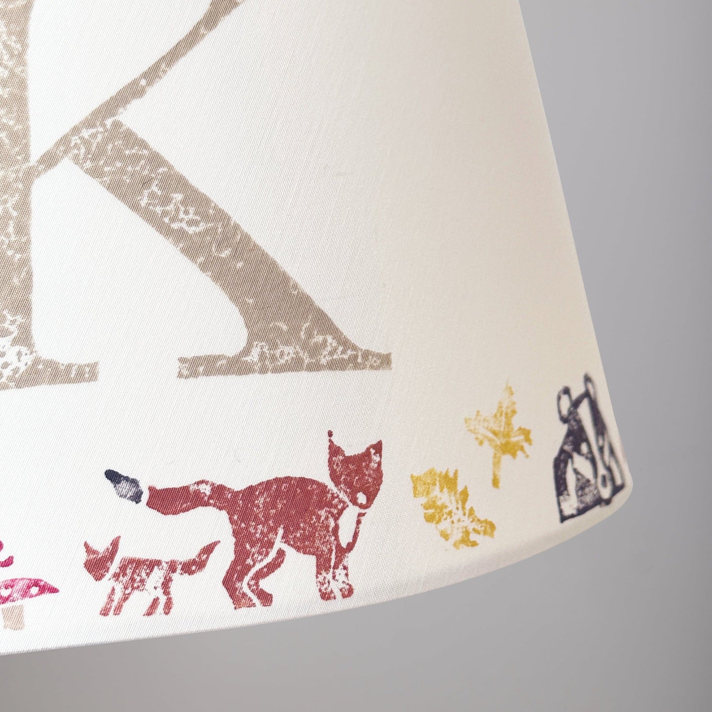 Close-up of a personalised kids lampshade with woodland animals design, featuring a fox and the letter K. Handmade empire lampshade ideal for kids bedroom decor, animal lampshade for boys lampshade or girls lighting. Perfect as a personalised kids gift, personalised christening present, or new parent gift.