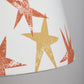 Close-up of a cream lampshade fabric showing bright orange lampshade and yellow lampshade star prints, highlighting the bold, playful design of this star lampshade.