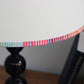 A bold stripe lampshade with a playful, colourful striped border in pink, red, blue, and green. This pretty lampshade adds a pop of striped lighting detail, perfect for modern interiors and striped lampshades UK collections.