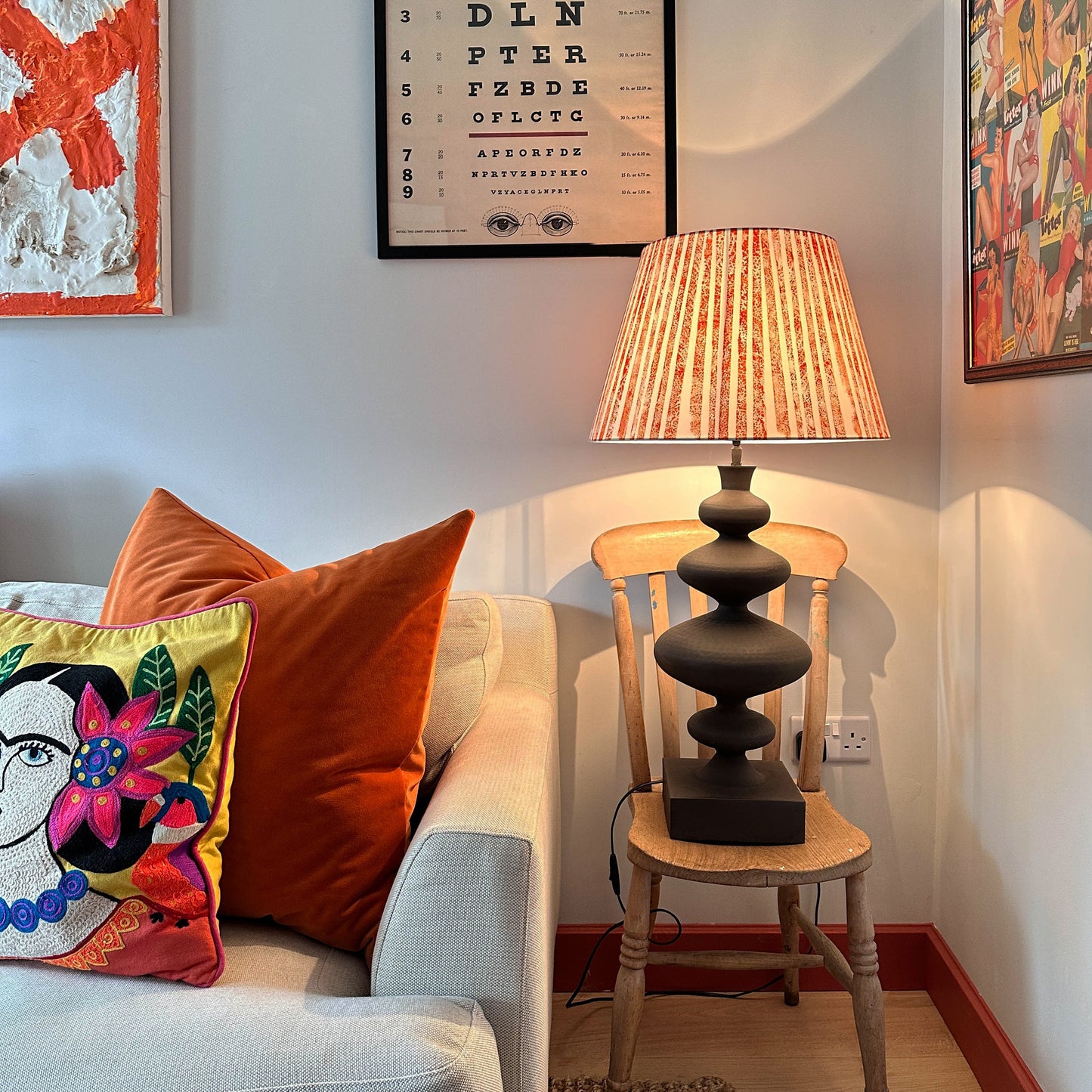 Striped orange lampshade on a chair next to a sofa