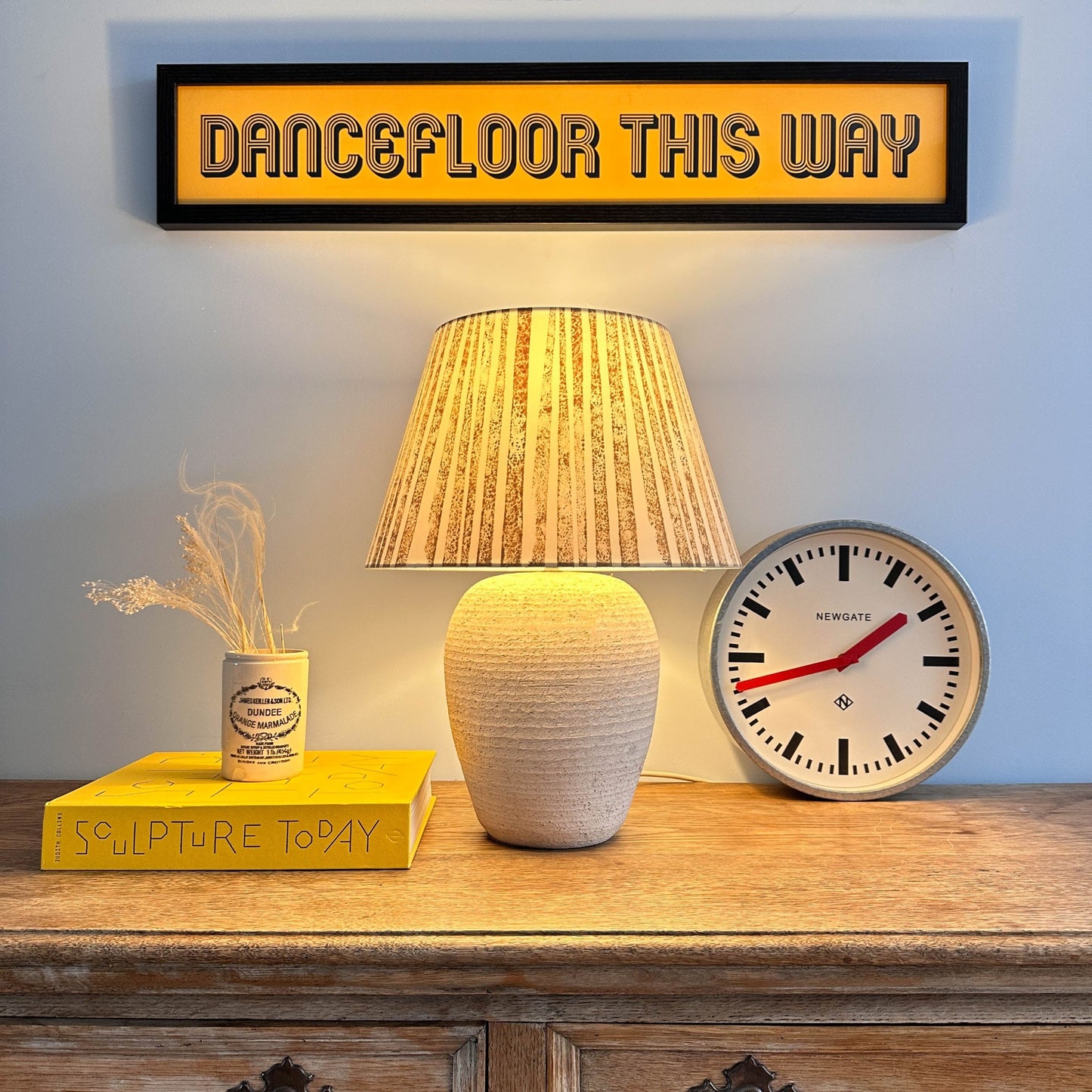 Brown striped lampshade on wooden sideboard with the light on