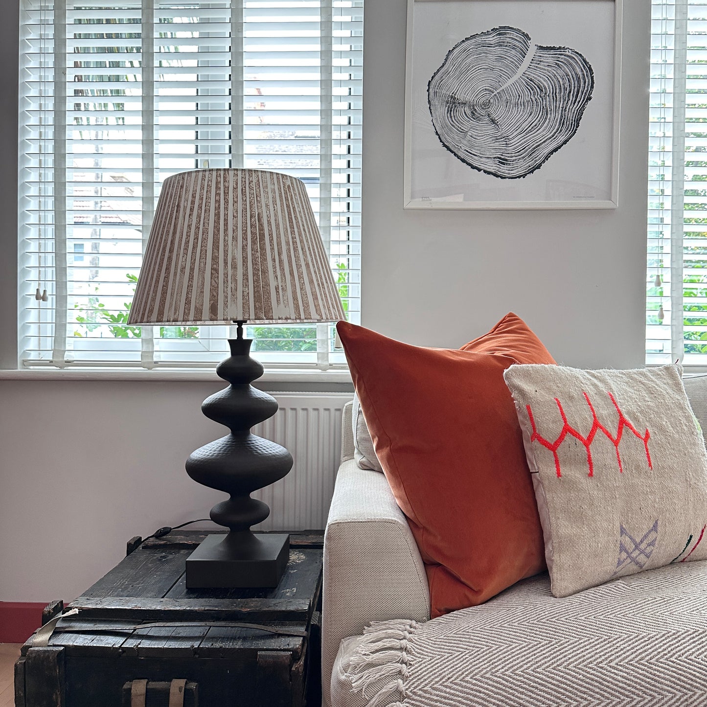 Striped brown lampshade on wooden coffee table next to cream sofa