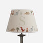 Personalised dinosaur lampshade with initial S, decorated with colourful dinosaurs, volcanoes, palm trees and cacti on a cream empire shade.