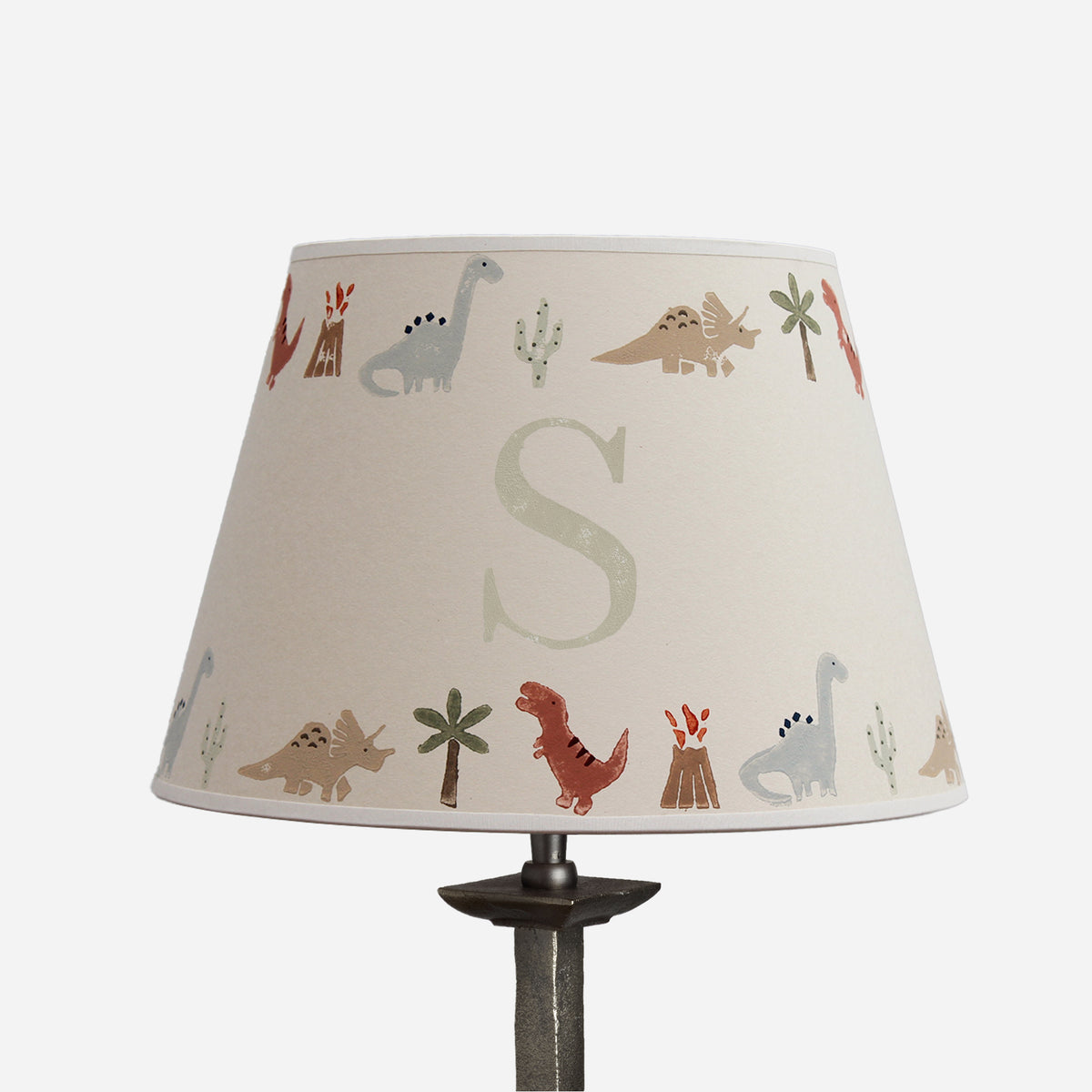 Personalised dinosaur lampshade with initial S, decorated with colourful dinosaurs, volcanoes, palm trees and cacti on a cream empire shade.