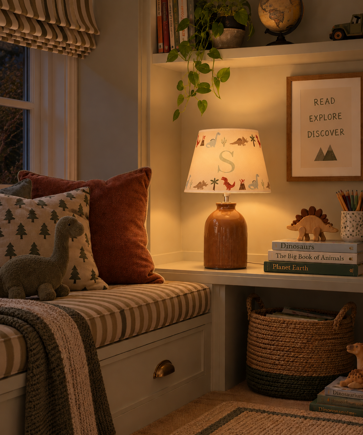 Cosy children’s reading nook at night with a personalised dinosaur lampshade featuring the initial S, styled with dinosaur books, toys and cushions.
