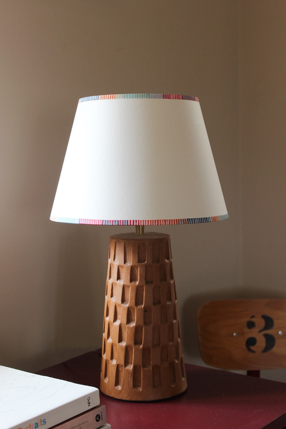 A colourful lampshade with bold striped trim, styled on a geometric wooden lamp base. This empire lampshade showcases striped lampshades UK craftsmanship.