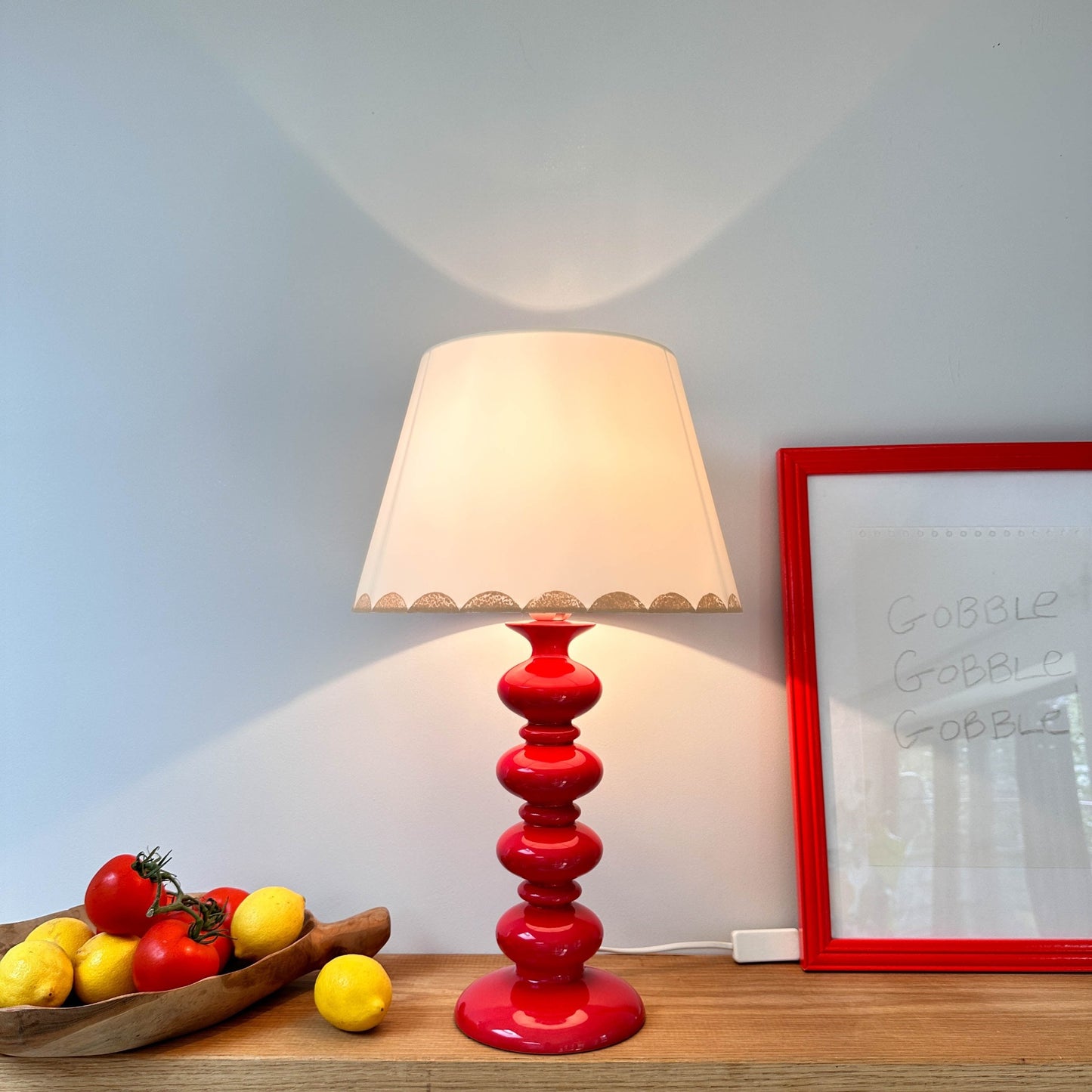 Pink scallop lampshade on red lamp with light on