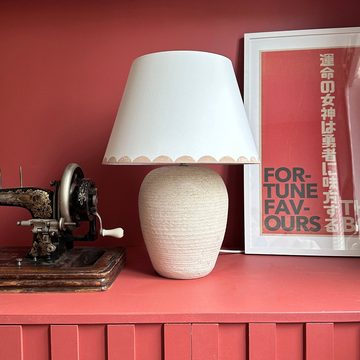 Pink scallop lampshade on cream lamp with red background