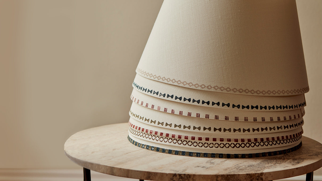 Stack of linen lampshades from the collaboration by Studio Zef and interiors designers Albion Nord, each hand-painted with geometric block-print patterns in earthy tones, creating unique geometric lighting for artisanal and contemporary interiors.