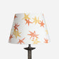 A stand-alone product shot of the Wonky Stars Lampshade in cream with scattered orange and yellow star prints. A bold lampshade and empire lampshade, perfect as empire shades for table lamps or kids lampshade styling.