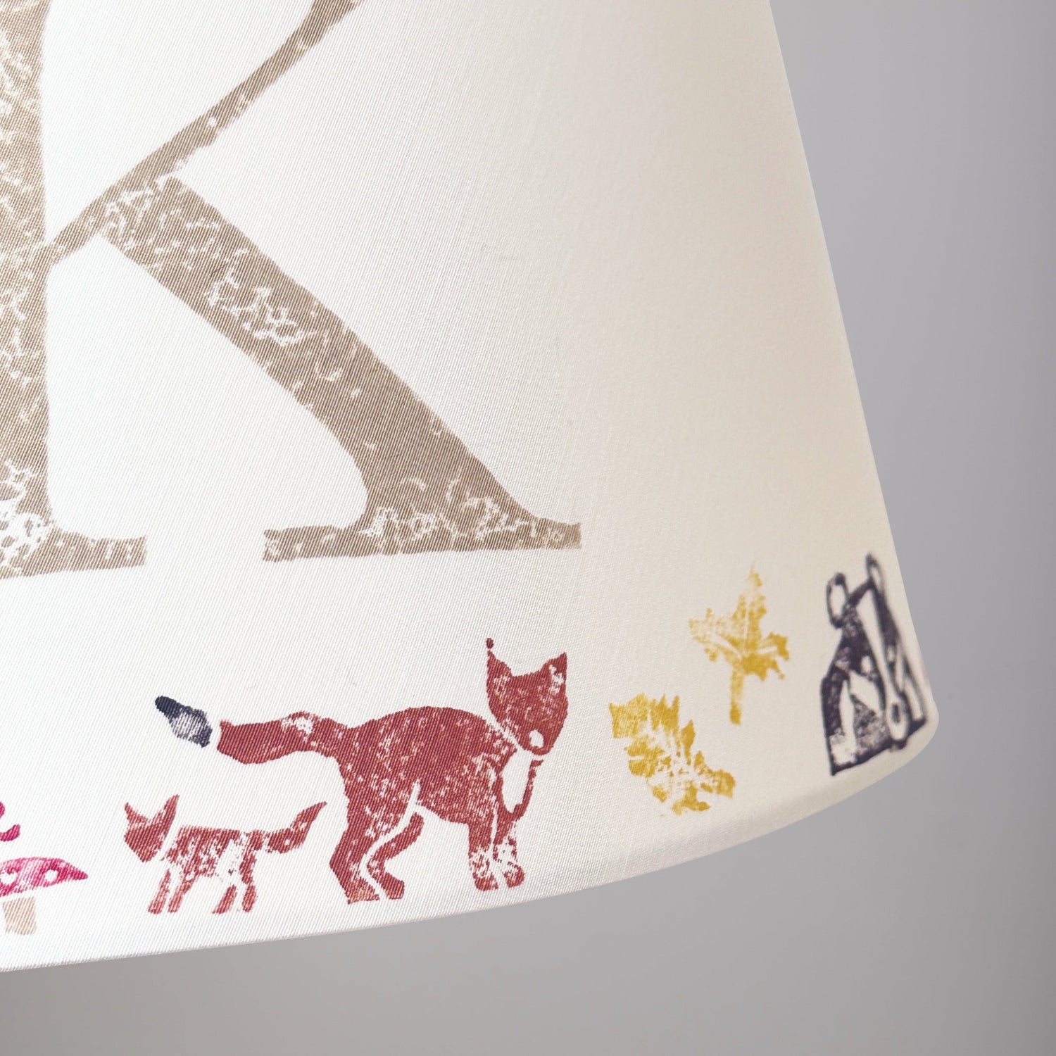 Close-up of a personalised kids lampshade with woodland animals design, featuring a fox and the letter K. Handmade empire lampshade ideal for kids bedroom decor, animal lampshade for boys lampshade or girls lighting. Perfect as a personalised kids gift, personalised christening present, or new parent gift.