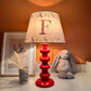 Empire lampshade for kids bedroom with woodland animals and personalised initial, lit to show warm kids lighting. A colourful lampshade and personalised kids gift perfect for bedtime reading.