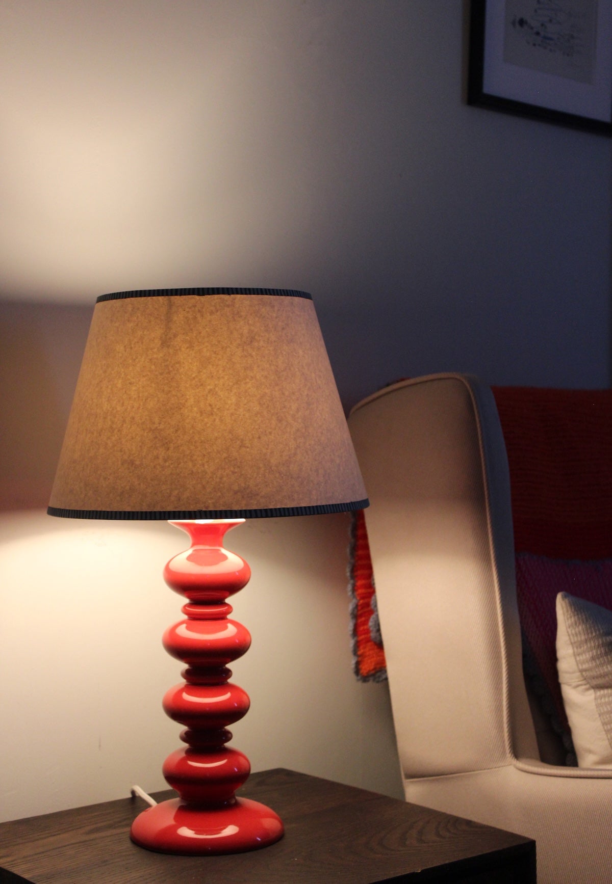 Empire light shade with bold hand-painted striped edge, glowing warmly on a red table lamp. A stylish striped lampshade bringing cosy striped lighting to modern interiors.